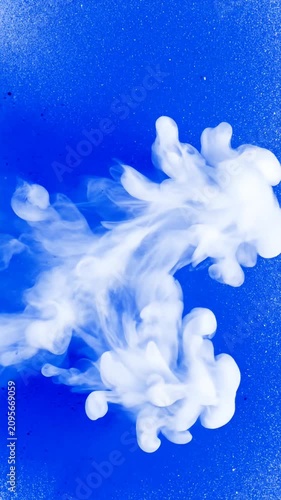 White ink cloud swirling in blue liquid.