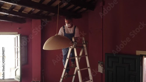 Man in overalls spray painting a pendant lamp