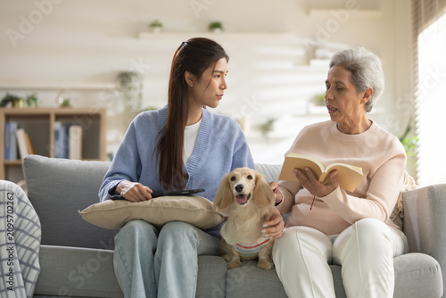 Tableau sur toile Serious young woman and senior mother talking on living room sofa with pet dog