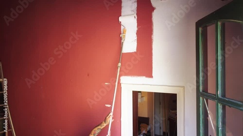 Tattooed man painting wall with white paint