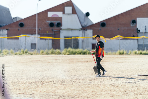 Foto Baseball coach raking infield dirt, preparing baseball field for an upcoming you