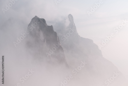 Schilderij op canvas High altitude landscape featuring jagged mountain peaks partially obscured by dense white fog