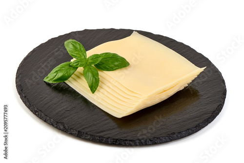 Sliced cheese with basil leaves on a black slate board