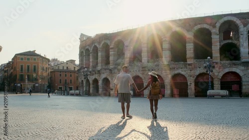 Verona Italy offers a romantic stroll through its historic streets. A couple walks hand in hand near the iconic Arena, basking in the warm glow of the setting sun.