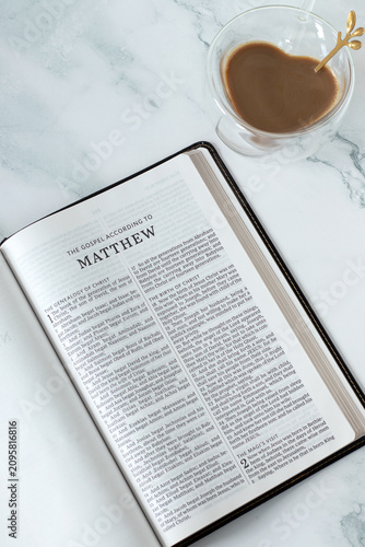Matthew gospel in holy bible book with coffee cup. Christian study and reading concept.