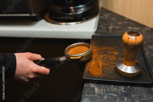 Quadro su tela A portafilter filled with freshly pressed ground coffee near a wooden tamper