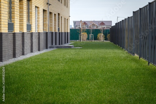 Fotografía Green lawn pathway running between fence and residential building in courtyard