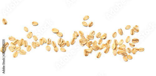 Scattered oat flakes on a clean white background.  Top view of oat flakes isolated.