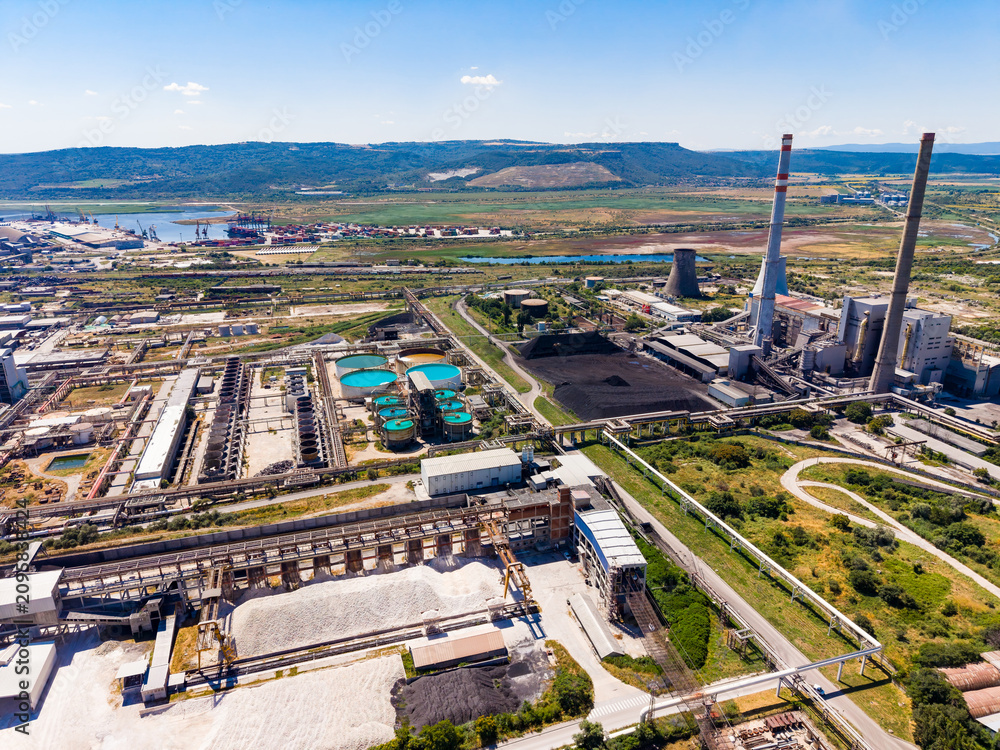 Obraz premium Industrial site with multiple structures and large water tanks located near a river in a dry area during daytime