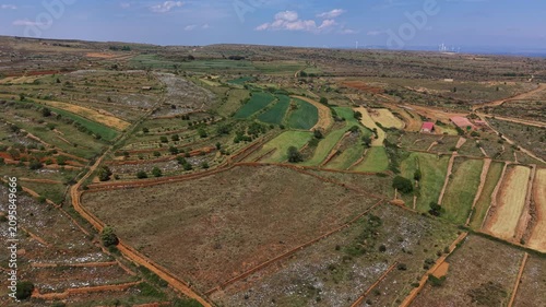 Aerial view of curved terraced agricultural fields divided by traditional dry stone walls in a patchwork landscape, wind turbines visible on the distant horizon, Maestrazgo, Teruel, Aragon, Spain