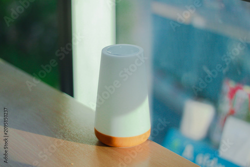 A modern white essential oil diffuser with a wooden base placed on a windowsill in soft natural light. Minimalist home decor creating a calm, relaxing atmosphere, perfect for wellness, aromatherapy, a