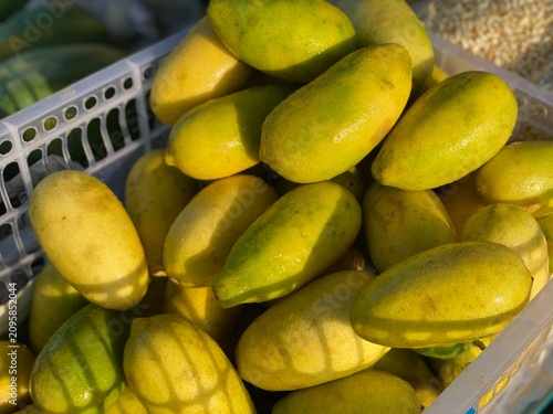 Fotografía Fresh yellow oblong lemons piled in a plastic basket at a street market