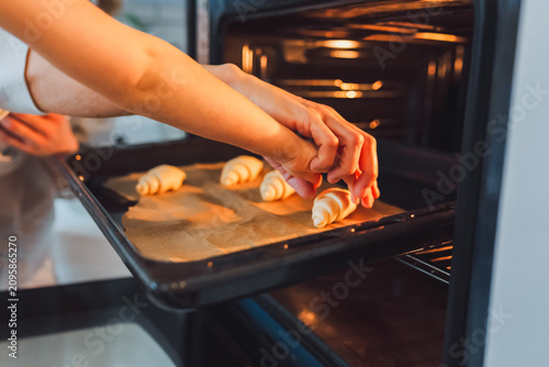 Obraz na płótnie Putting croissants on a baking sheet into the oven.