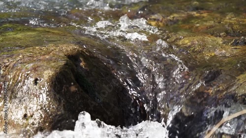 4x slow motion close-up video of turbulent mountain river with crystal-clear water tumbling over small rapid of exposed rocks, boulders. Angle view of current directly above, nature footage, 30 fps