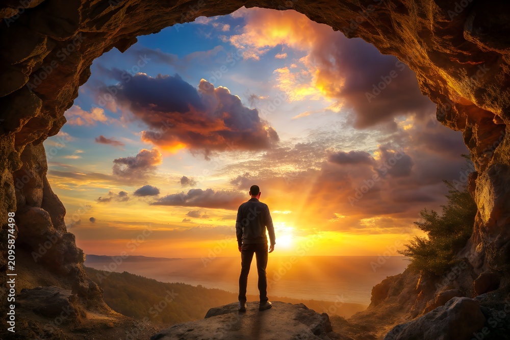 Fototapeta premium International migrants day concept: Silhouette humble man standing on cave autumn sunset background