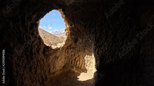 Cave window framing snow peaks rock Jhong Chhoser cave Upper Mustang Nepal landscape