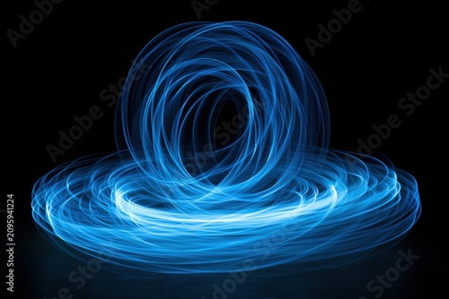 Blue light trails swirling in concentric circles against a dark background in a long exposure shot for futuristic technology branding