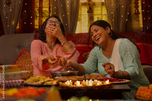 Mother-in-law and daughter-in-law making laddoo on the occasion of Diwali