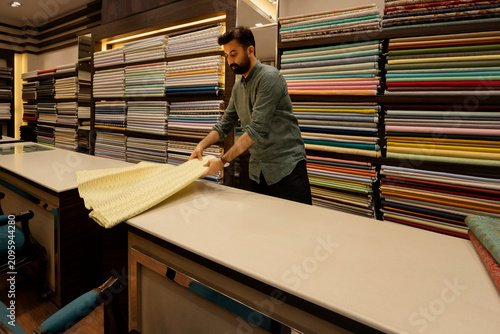 Man opening a fabric roll in a clothing store 