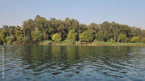 Scenic view of the Seyhan River flowing through central Adana, Turkey, framed by dense eucalyptus trees and common reeds in the lush Eski Baraj greenbelt.