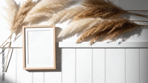 Frame with pampas grass on white wall.