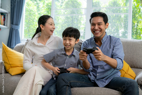 Cheerful young family with a little child laughing together in the living room, representing happiness, love, bonding, and sweet home concept.