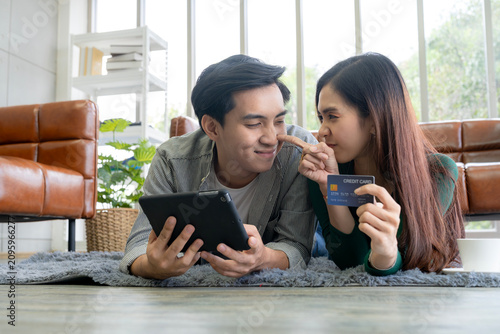 Cheerful man and woman smiling together while using a laptop and credit card for e-commerce purchase, representing smart consumer and safe digital payment.