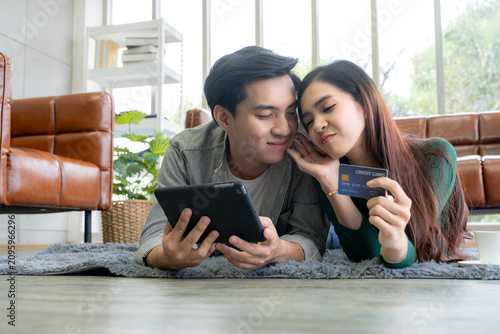Cheerful man and woman smiling together while using a laptop and credit card for e-commerce purchase, representing smart consumer and safe digital payment.