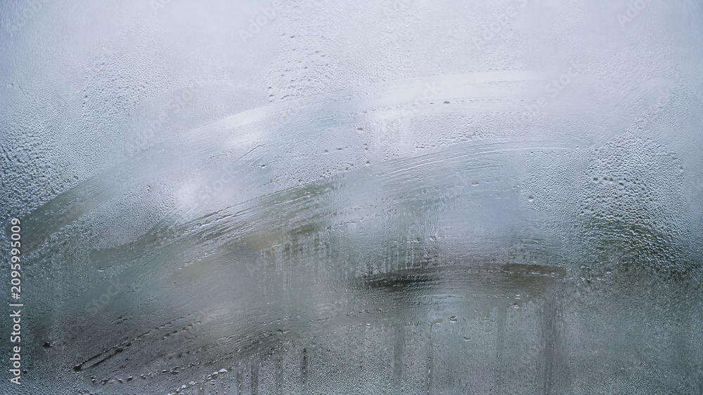 Fototapeta premium Condensation on glass window surface with blurred view outside. Water droplet and vapor moisture texture, cold weather concept. Gray background for text overlay or design backdrop effect