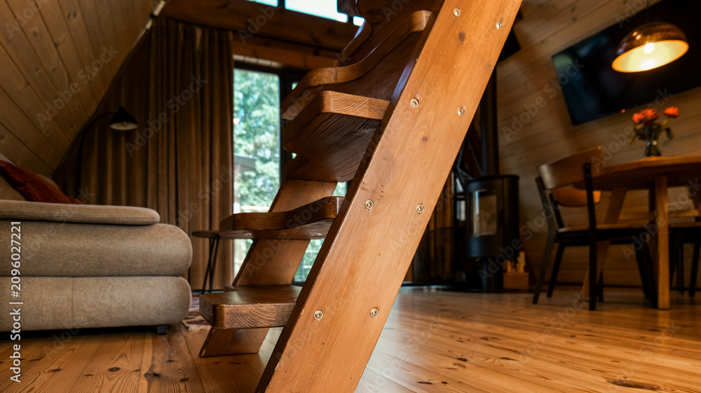 Obraz premium Cozy wooden cabin interior with a unique staircase and comfortable living space