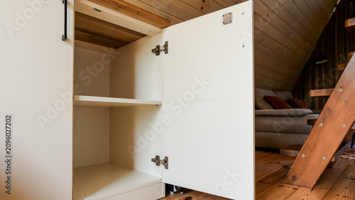 Modern white cabinet with open door revealing empty shelves and wooden interior details