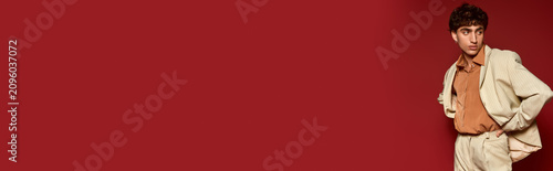 Cuadro en lienzo Handsome young man showcases stylish attire against a vibrant backdrop of red co