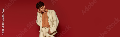 Tableau sur toile Handsome young man showcases elegance in stylish attire against a vibrant red backdrop