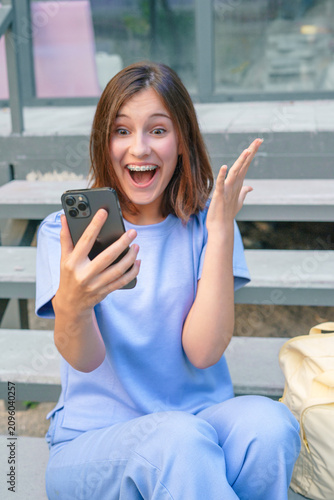 Fotografie teenage girl with dental braces holding smartphone looking at screen with wide-e