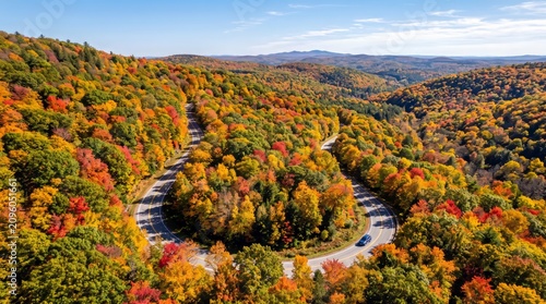 Winding asphalt road through autumn forest with colorful foliage and distant mountain range highway pavement