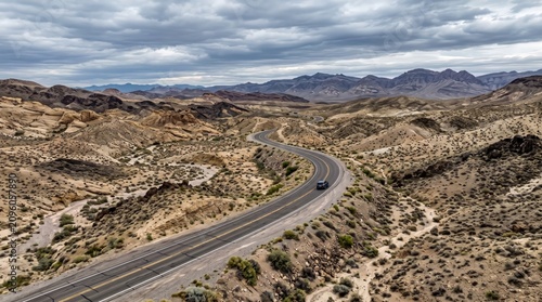 Winding asphalt road through desert landscape with mountainous backdrop under cloudy skies highway pavement travel