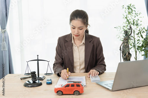 Fotografía Asian female lawyer or insurance agent reviewing contract document with car model and money cash on desk for legal protection or auto loan concept
