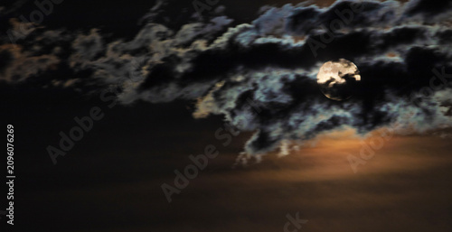 Full moon peeking through the clouds in Southern Arizona