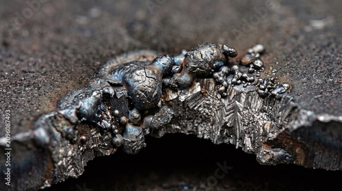 Close-up texture of a rough cut industrial steel edge with solidified metal spatter and slag