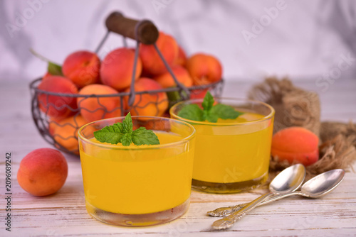 Fotografie Apricot jelly in short glasses against a background of fresh apricots