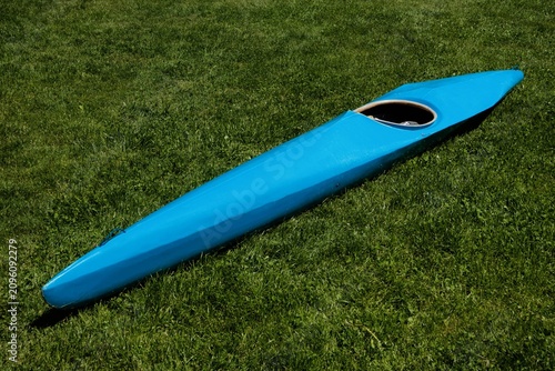 Blue Racing Kayak Hull Lying on Green Grass.