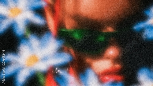 An abstract, grainy image depicting a person in sunglasses surrounded by vibrant blue and white flowers.