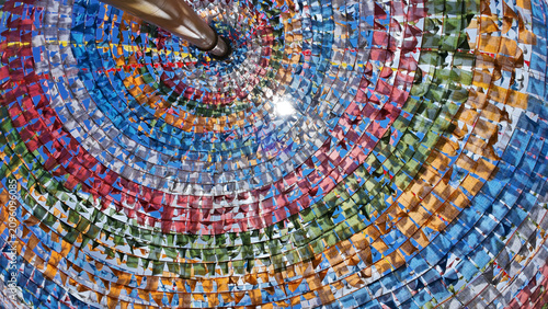 Konstfotografi Wide-angle upward shot of spiral colorful prayer flags tunnel with sunlight flar