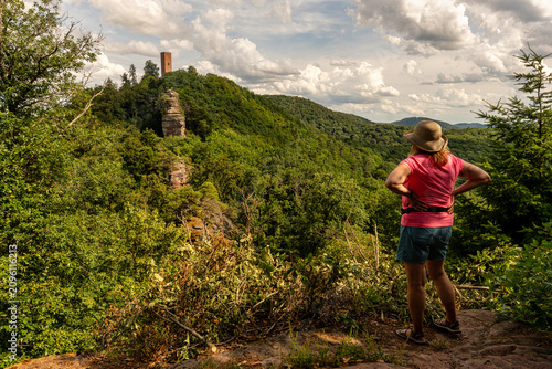 фотографія Wanderin schaut auf einem Aussichtsfelsen auf dem Burgenweg bei Annweiler auf di