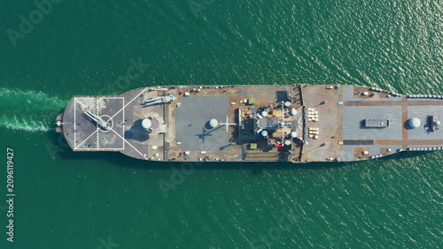 Majestic Amphibious Assault Ship. Navy aircraft carrier moves smoothly across tranquil dark green ocean, representing naval power and strategic readiness in serene environment.