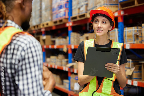 Workers collaborating while reviewing inventory management with each other in a warehouse storage