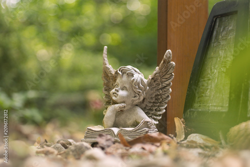 Foto Kleine Engelsfigur am Grab steht vor dem Holzkreuz, freier Hintergrund, keine Na