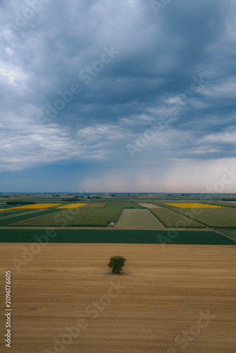 A massive, powerful summer storm looms over vast fields
