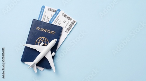 Navy blue passport with airplane model and boarding tickets on light blue background
