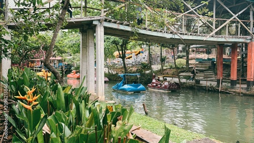Fotografía Leisurely canal boat ride in a lush tropical park with an overhead bridge and vi